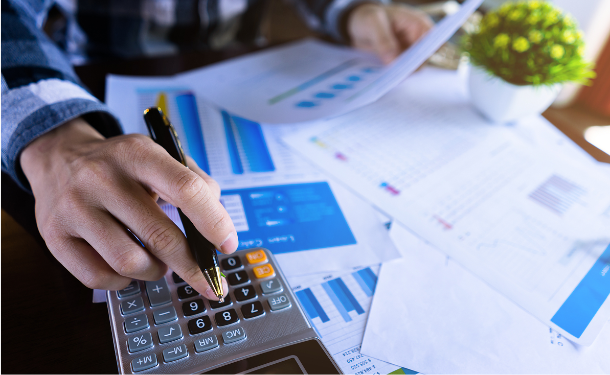 Person using calculator and reviewing financial documents.
