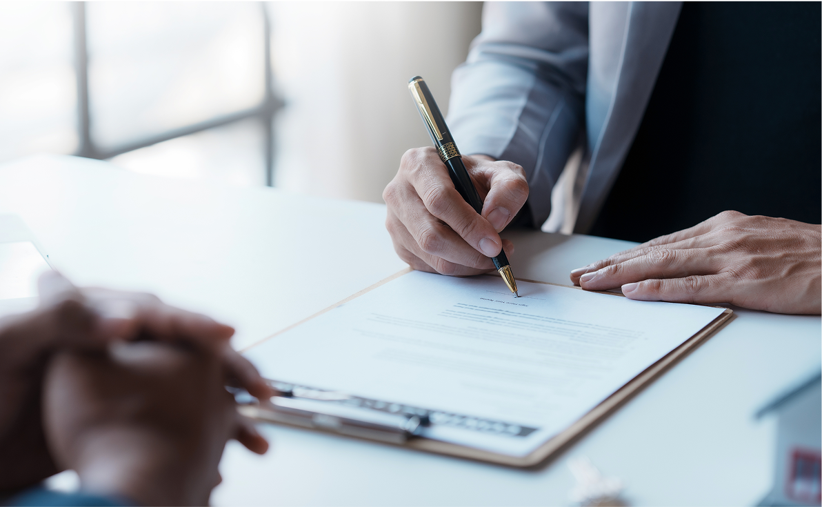 Person signing a document on a table.