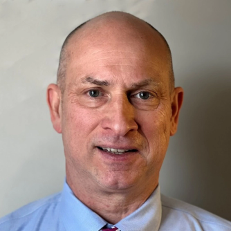 Portrait of a middle-aged man in a blue shirt and tie.